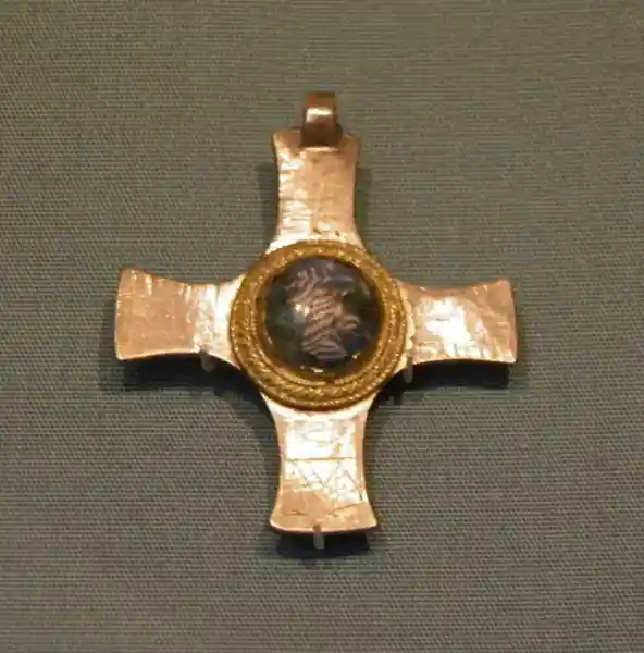 A cross pendant with a solar disc in the center